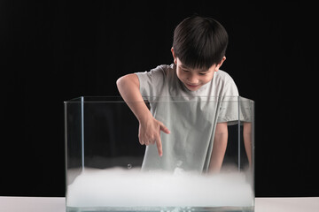 An Asian boy does an experiment with dry Ice or frozen carbon dioxide in the water tank.