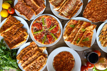  Traditional Turkish cuisine. Pizza, pita, pidesi, sucuk, hummus, kebab. Many dishes on the table. Serving dishes in restaurant. Background image. Top view, flat lay