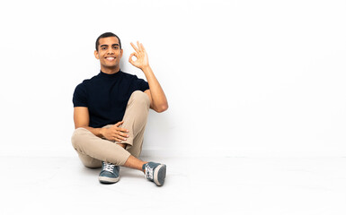 African American man sitting on the floor showing ok sign with fingers