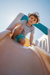 The little boy at the top of the slider prepares to slip and looks down.