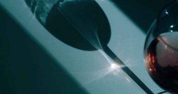the sun's rays are refracted through a wine glass casting a shadow on the table, caustic light, optical effect