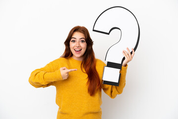 Young redhead woman isolated on white background holding a question mark icon with surprised expression