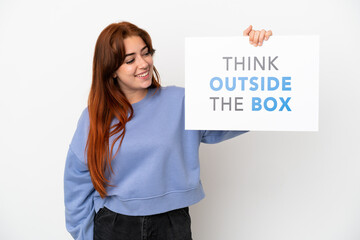 Young redhead woman isolated on white background holding a placard with text Think Outside The Box
