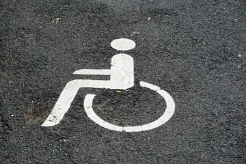 Behindertenparkplatz mit weißem Zeichen auf grauem Asphaltboden 
