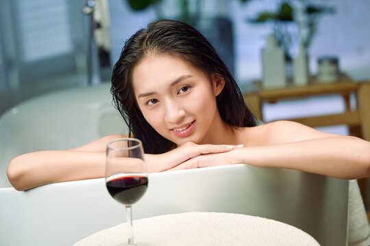 The bathtub beautiful young woman and wine
