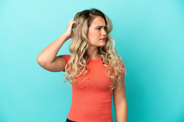 Young Brazilian woman isolated on blue background having doubts while scratching head