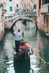 Fototapeta na wymiar Venice, Italy - May 25, 2019: view of gondolas traffic in canal singer at boat