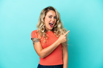 Fototapeta premium Young Brazilian woman isolated on blue background surprised and pointing side