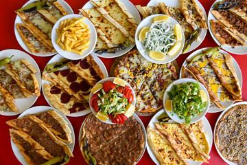 Fototapeta na wymiar Traditional Turkish cuisine. Pizza, pita, pidesi, sucuk, hummus, kebab. Many dishes on the table. Serving dishes in restaurant. Background image. Top view, flat lay