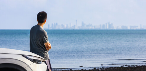 Asian man looking at the urban business skyline of financial district over the lake for future...
