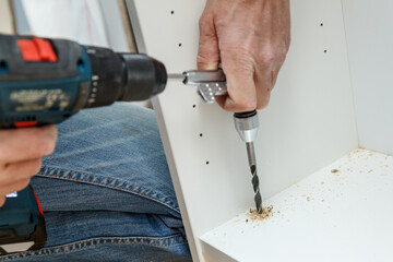 Carpenter using angle drilling bit adapter in furniture making process.