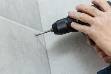 Rapairman drilling ceramic tile on a wall.
