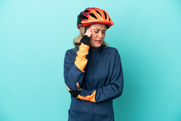 Young cyclist woman isolated on blue background with headache