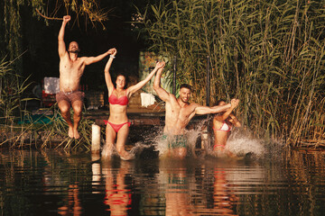 Group of young people enjoy a summer day and jump into the river