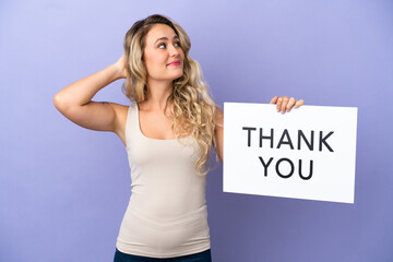 Young Brazilian woman isolated on purple background holding a placard with text THANK YOU and thinking