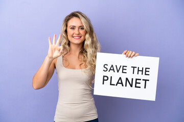 Young Brazilian woman isolated on purple background holding a placard with text Save the Planet and celebrating a victory