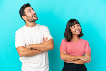 Young couple isolated on blue background looking up while smiling