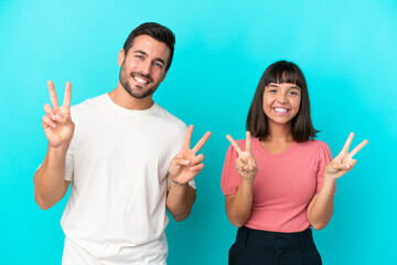 Young couple isolated on blue background smiling and showing victory sign with both hands