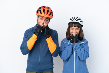 Young cyclist couple isolated on white background smiling a lot while covering mouth