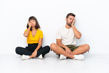 Fototapeta premium Young couple sitting on the floor isolated on white background with surprise and shocked facial expression