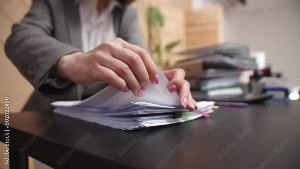 Poster closeup female hands of an office worker sorting through sheets from stack of documents. female mana