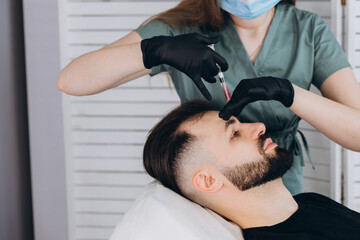 Mesotherapy procedure. A cosmetologist performs a mesotherapy procedure on the head of a young man....