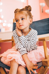 Fototapeta premium Stylish little girl in a beauty salon for children where she made a beautiful hairstyle. Beauty and kid fashion with healthy hair.