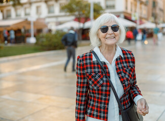 Happy pensioner female walking outdoors in town