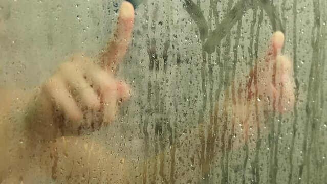 woman taking shower drawing heart on misty glass