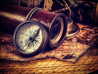 Travel geography navigation concept background - old vintage retro compass, spyglass and rope on ancient world map