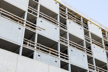 Unfinished glass and concrete facade with a scaffold around on office building construction site