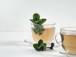 Fragrant mint tea on a light background. A cup of tea, a bunch of fresh mint. Herbal tea application concept.