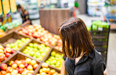 Woman in a supermarket at the shelf for fruits shopping apple