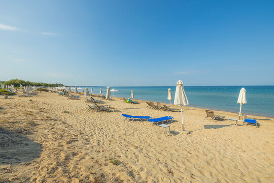 Beautiful View Of Empty Sandy Beach With Sun Loungers And Parasols On Mediterranean Coast. Greece.