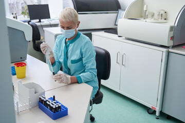 Woman doing blood tests at desk in modern laboratory