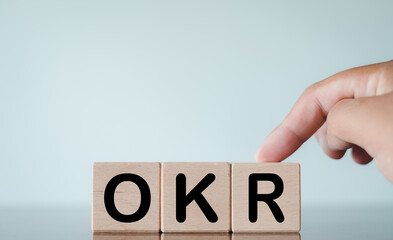 OKR or Objectives, Key and Results Concept.,OKR acronym on wooden cube with hand putting over white background.