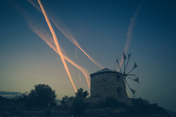 Windmills in Chios Island with airplane trails at the background