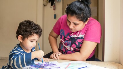 boy painting with his mom with brushes and paint