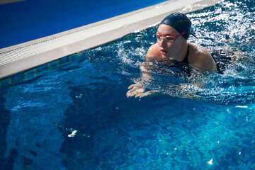 Athletic woman is swimming in the pool during training