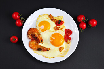 Fried eggs with shrimp in a frying pan.