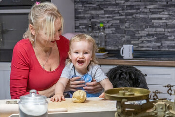 Obraz premium Laughing lttle helper child boy is posing with his grandmother and dog in domestic kitchen