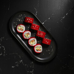 Traditional delicious fresh sushi roll set on a black background. Sushi roll with rice, nori, tobiko caviar, avocado. Sushi menu.