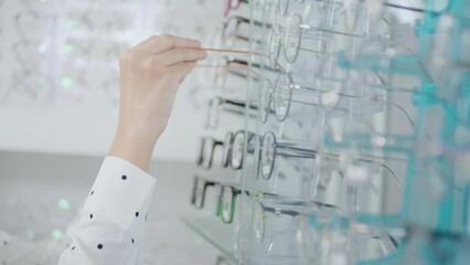 Young female customer choosing glasses in optical center, Eyecare concept.