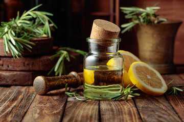 Bottle of essential oil, rosemary, and lemon.