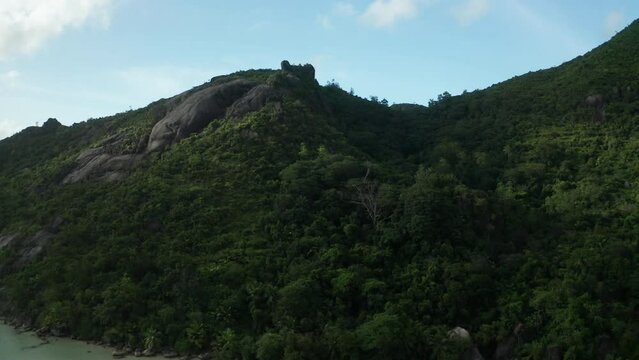 Aerial crane over Baie Ternay beach to top of rock with huge boulders