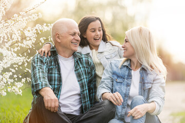 senior man grandfather sitting on outdoor in the park. Elderly retired male relax and enjoy outdoor activity together with daughter and granddaughter. Family relationship concept
