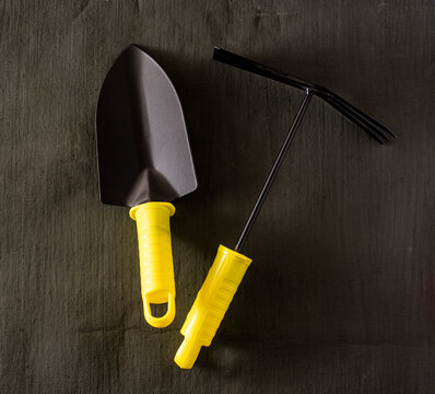 garden tools shovel and rake on a dark tarpaulin.