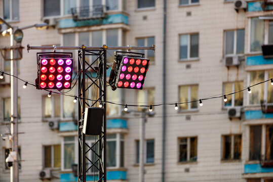 Street Lighting With Red And Pink Spotlights On The Background Of An Apartment Building In Blur.