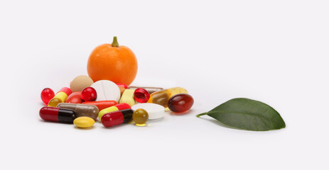 Vitamins, pills, tangerine fruit, leaf and tablets on light gray copy space background.