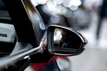 Side rear-view mirror on a modern car on blurred traffic background